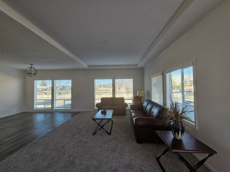 Living room with a brown leather sofa, coffee table, and large windows.